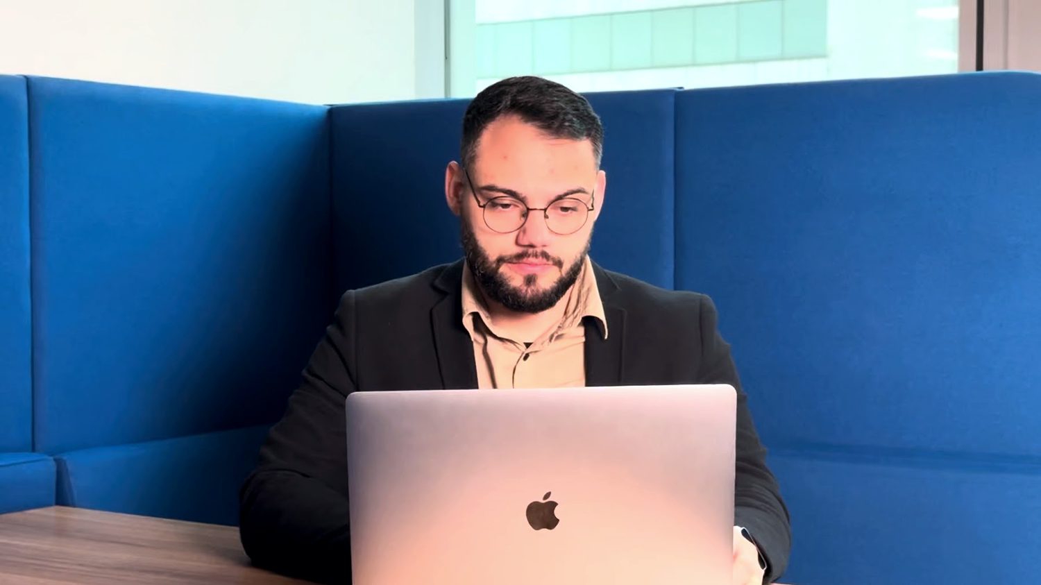 Matheus Orlando em cabine azul, trabalhando no notebook